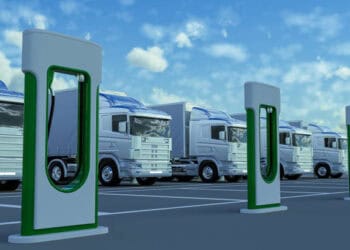 A group of trucks parked in front of a charging station, complying with EU trade rules.