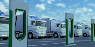 A group of trucks parked in front of a charging station, complying with EU trade rules.