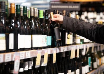 A man selects a bottle of wine in a store.