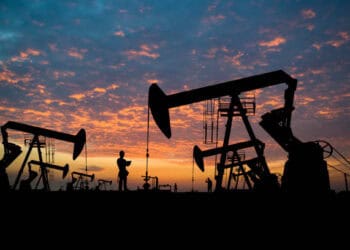 Silhouetted oil pumps at sunset; OPEC+ geopolitical tensions. - Supply Chain News