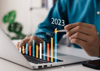 A man is working on a laptop analyzing economic stories and finance graphs.