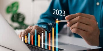 A man is working on a laptop analyzing economic stories and finance graphs.