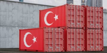 Three red shipping containers with the Turkish flag on them, representing import-export tariffs adjustments.