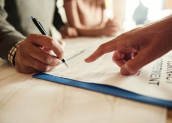 Two people signing a contract at a table, ensuring international law compliance and transparency.