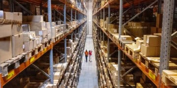 Two people walking through a warehouse full of boxes, observing the impact of China Tariffs on U.S. imports from Taiwan.