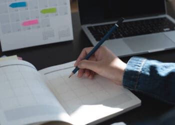A person using a pen to write on a calendar for event-planning purposes.