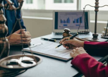 Two people signing a document regarding Section 201 tariffs on solar panels at a desk.