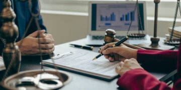 Two people signing a document regarding Section 201 tariffs on solar panels at a desk.