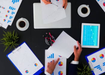 A group of people sitting around a table, discussing sustainable development and COP28 preparations with papers and graphs.