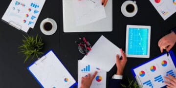 A group of people sitting around a table, discussing sustainable development and COP28 preparations with papers and graphs.