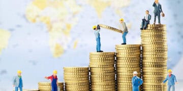 A group of figurines standing on top of stacks of coins, analyzing year-end economic data.
