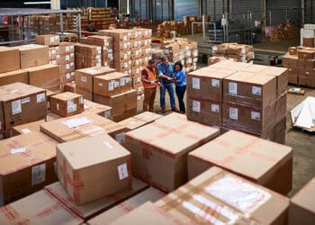 Two people standing in a warehouse full of boxes, examining industrial goods imported under Switzerland's tariff-free import policy.