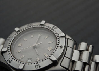 A close up of a Rolex watch on a black surface.
