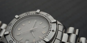 A close up of a Rolex watch on a black surface.