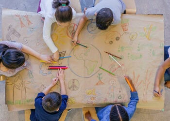 A group of children at the Utah International Leadership Academy showcasing their foreign relations skills by collaboratively drawing on a piece of paper.