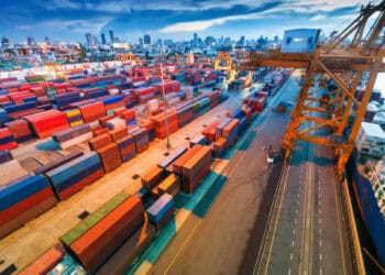 An aerial view of a container port at dusk, showcasing the bustling activities related to the Asia-Europe Trade Route.