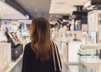 A woman browsing cosmetics in a store, considering the changing consumer dynamics and pricing strategy in the luxury market.