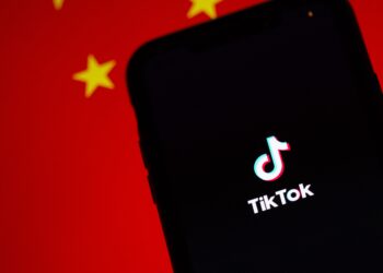 TikTok logo on smartphone screen against blurred Chinese flag background. App's endurance amidst bans. - Supply Chain News