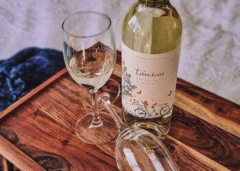 An exquisite bottle of Australian wine and a delicate glass on a polished wooden tray.