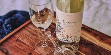 An exquisite bottle of Australian wine and a delicate glass on a polished wooden tray.