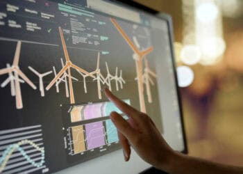 A person pointing at a computer screen displaying wind turbines, highlighting their significance in global trade.