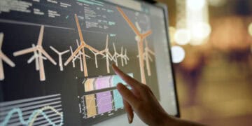 A person pointing at a computer screen displaying wind turbines, highlighting their significance in global trade.