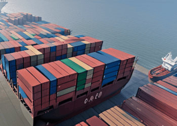 A massive container ship is docked in the ocean, suggesting its significant presence amidst the vast seascape.