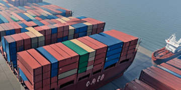 A massive container ship is docked in the ocean, suggesting its significant presence amidst the vast seascape.