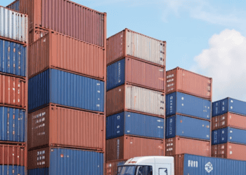 Shipping containers stacked high at a logistics facility. Trucks transport goods, boosting the supply chain workforce. - Supply Chain News
