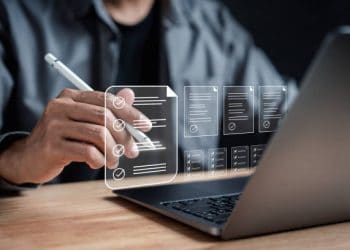 Person using a stylus on a laptop, reviewing digital checklists and documents related to East African flower exports and UK trade agreements. - Supply Chain News