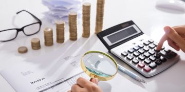 Close-up of invoice, calculator, coins, and magnifying glass; preparing for Chief Procurement Officer Summit. - Supply Chain News