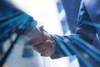 Businesspeople shaking hands, symbolizing a trade agreement or negotiation impacted by increased tariffs. - Supply Chain News