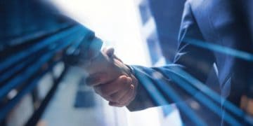 Businesspeople shaking hands, symbolizing a trade agreement or negotiation impacted by increased tariffs. - Supply Chain News