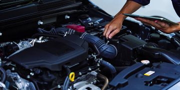 Mechanic inspecting car engine with digital tablet - Supply Chain News