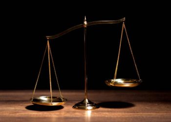 Golden scales of justice on a wooden surface. Trade debate. - Supply Chain News
