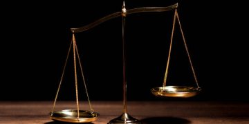 Golden scales of justice on a wooden surface. Trade debate. - Supply Chain News