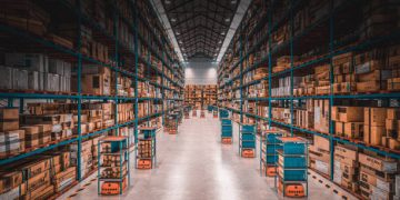 Warehouse interior with rows of boxes and autonomous robots, potentially impacted by US tariffs on imported goods. - Supply Chain News